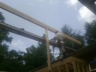 Carpenter setting a ridge beam over a new addition frame — Ice Dam Removal by Roofing Brothers in Yellow Spring