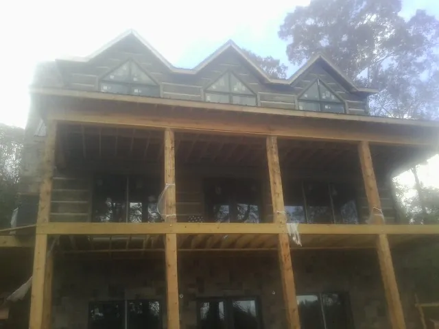 Dormers and porch framing on a large log home under construction — Roof Coating work by our crew in Yellow Spring