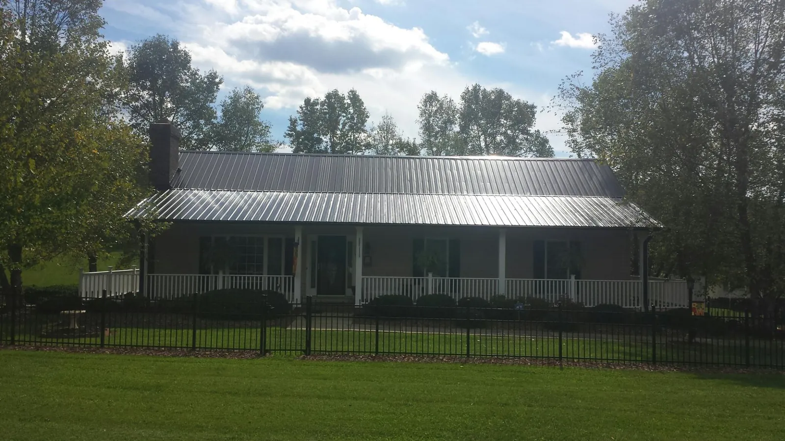 Gray metal roof on a brick ranch with a full width front porch — Gutter Guard Installation work by our crew in Yellow Spring