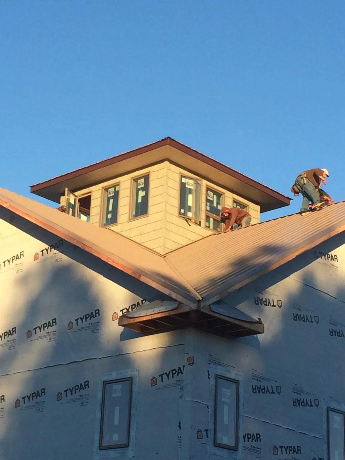 Roofers working around a rooftop cupola on a new metal roof at sunset — Roof Waterproofing in Yellow Spring by Roofing Brothers